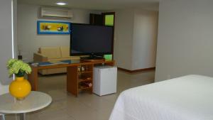 a living room with a tv and a bed and a table at Hotel Elite 1 in Nossa Senhora dos Milagres