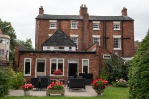 a large red brick building with chairs and flowers at Abbots Mead Hotel in Shrewsbury