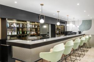 a bar with white chairs and a counter with liquor bottles at Danubius Hotel Hungaria City Center in Budapest