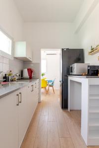a kitchen with white cabinets and a black refrigerator at Haifa Hadar Urban Apartment in Haifa