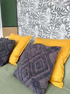 - un lit avec 2 oreillers jaunes et un mur dans l'établissement Havre de paix moderne, fibre,RER B direction Paris, à Fontenay-aux-Roses
