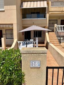 a building with an outdoor table with an umbrella at Tranquil Self Catering Golf Course Apartment in Alicante