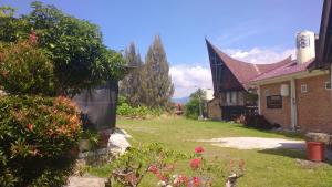 a house with a yard with flowers in front of it at Bernard's Guest Houses in Tuktuk Siadong