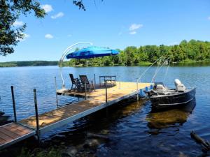 Un muelle con un barco y una sombrilla en el agua. en Dragonwood Bunk House, en Abbot Village