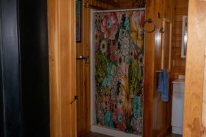 y baño con ducha y cortina de ducha con motivos florales. en Dragonwood Bunk House, en Abbot Village