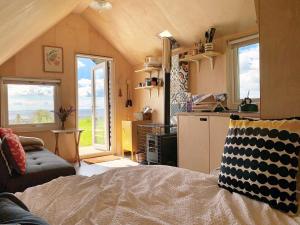een woonkamer met een bed en een keuken met ramen bij St Oswald Beach Hut Alnmouth in Alnmouth