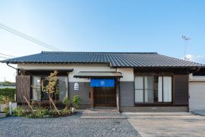 ein Haus mit einem blauen Schild davor in der Unterkunft 一棟貸切の和風プライベートヴィラ プール花火バーベキュー in Fukutsu