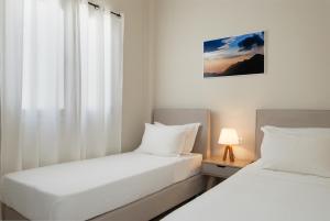 two beds in a small room with a window at Villa Grotta in Kamarai