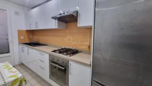 a kitchen with white cabinets and a stainless steel refrigerator at Location saisonniere Appartement Sousse Khezama in Kasnadar +9 photos