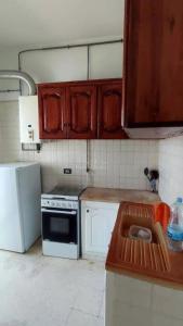 eine Küche mit Holzschränken und einem Spülbecken darin in der Unterkunft location saisonniere S2 a corniche in Kasnadar