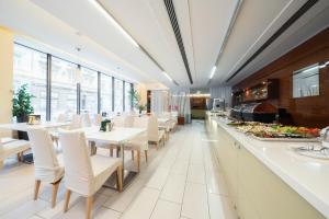 restauracja z białymi stołami, krzesłami i oknami w obiekcie Hotel Ehrlich Prague w Pradze