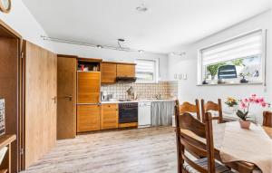 cocina con armarios de madera, mesa y comedor en 2 Bedroom Nice Apartment In Hildfeld, en Winterberg