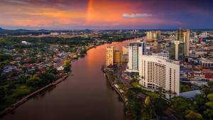 a city with a rainbow in the sky over a river at Newly Riverbank suites 408 in Kuching