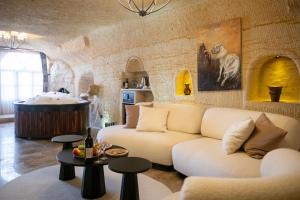 a living room with a white couch and a tub at Urgup Evi Cave Hotel in Ürgüp