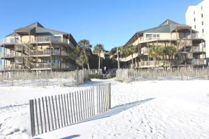 two condos on the beach next to a fence at Sandpiper 1C- Stylish Gulf-side affordable in Gulf Shores
