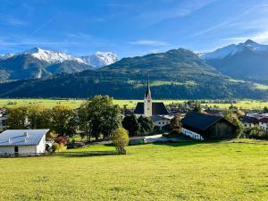 a small village with a church and mountains in the background at Panoramic Penthouse 10 min to Zell am See & Kaprun in Piesendorf