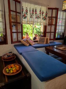 a room with blue cushions and a table and windows at Vagia Traditional, Aegina Island in Vaia