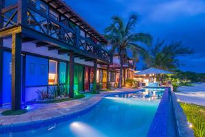 a villa with a swimming pool at night at Chez Pitu Praia Hotel in Búzios