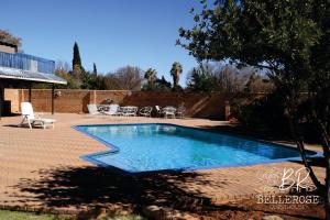a swimming pool in a yard next to a brick wall at Bellerose Guesthouse in Klerksdorp