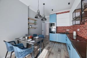 eine Küche mit blauen Schränken und einem Tisch mit Stühlen in der Unterkunft Роскошные Двухкомнатные Апартаменты in Almaty