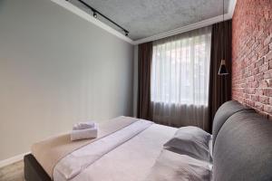 ein Schlafzimmer mit einem Bett und einer Ziegelwand in der Unterkunft Роскошные Двухкомнатные Апартаменты in Almaty