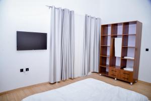 - une chambre avec une télévision et une étagère dans l'établissement The Milon Apartment, à Kigali