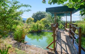 een vijver in een tuin met een houten brug bij Nice Apartment In Magliano In Toscana in Magliano in Toscana