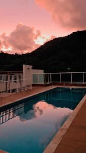 a swimming pool with a sunset in the background at Apartamento lumier 109 in Ubatuba