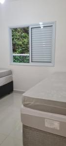 a white room with a bed and a window at Apartamento lumier 109 in Ubatuba