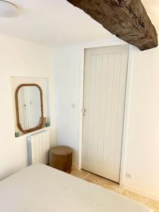 una camera da letto con porta bianca e specchio di Maisonnette rénovée entre mer et montagne avec 4 couchages au cœur du village médiéval de Tourrettes sur loup proche st Paul de vence Grasse Gourdon Nice Cannes a Tourrettes-sur-Loup