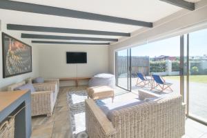a living room with a couch and chairs and a tv at Land's Edge Eco Friendly Cottages and Apartments in Struisbaai