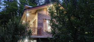 a house with a balcony in the woods at night at Hercue's Hillside Homestay in Shirir