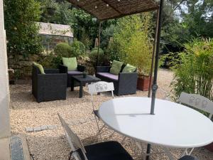 un patio con tavolo e sedie bianchi di Maison d'hôtes les Jardinettes en Luberon a Villelaure