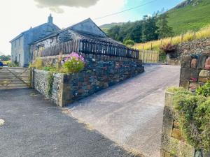 a stone wall next to a house with a flower pot at Stunning character cottage near Keswick in Threlkeld
