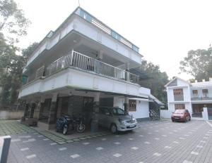 Natureland Homestay في كوتايم: مبنى فيه سيارة متوقفة في موقف للسيارات