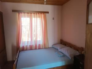 a small bedroom with a bed with a window at πλατανα Αστρους Αρκαδίας χωριατικο σπίτι για φυση και ηρεμία in Rounaíika
