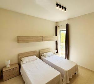 une chambre avec deux lits et une fenêtre dans l'établissement Monita 113, Seaside Apartment with Access to Pool and Pleasant Views, à Marsaskala