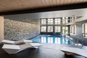 a pool in a building with a stone wall at Hotel ZAWRAT Ski Resort & Spa in Białka Tatrzanska