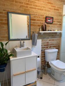 a bathroom with a sink and a toilet and a mirror at Casa charmosa em Juquehy cercada de verde, 2 quartos com churrasqueira in São Sebastião