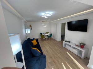 a living room with a blue couch and a flat screen tv at MK Apartments in Piatra Neamţ
