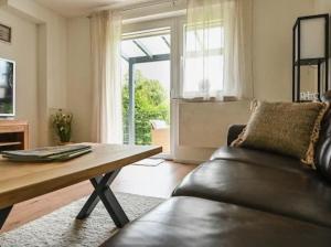 a living room with a leather couch and a wooden table at Entspannung und Erholung, Ferienwohnung mit traumhaftem Blick in die Natur in Oberaurach