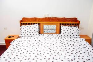 a bed with a black and white comforter and pillows at jodapartment in Gasanze
