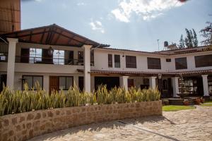 a large white building with a stone wall at Oro Andino Lodge in Caraz