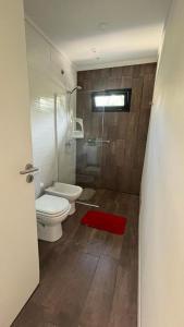 a bathroom with a toilet and a shower and a red rug at Casa Fresno Casas Atahualpa 2 in Mar del Plata