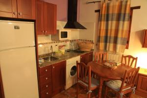a kitchen with a table and a white refrigerator at Alojamientos Rurales Cortijo Las Golondrinas in Alhama de Murcia