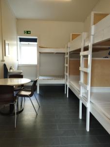 Camera con 2 letti a castello, tavolo e sedie. di Bergistangi Hostel a Norðurfjörður