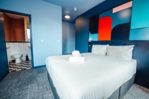 a bedroom with a large white bed and a bathroom at Kabannas Liverpool in Liverpool