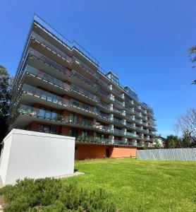 an apartment building with a lawn in front of it at Apartamenty Coastal Comfort Kołobrzeg in Kołobrzeg