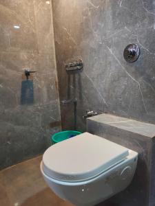 a bathroom with a toilet and a stone wall at Parmeshwar Lodge in Tuljapur