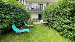 two chairs sitting in the grass in front of a house at 2 pièces avec jardin Fleur Marine bord de mer Cabourg in Cabourg +3 photos